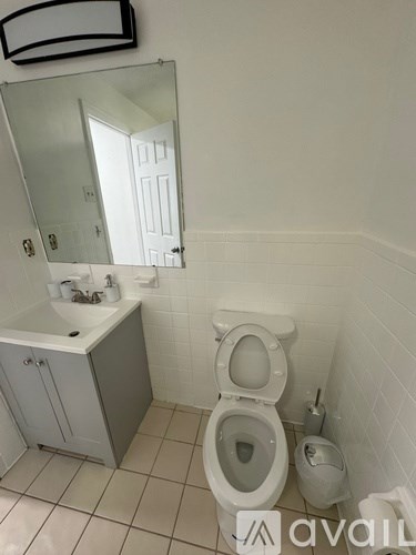 A bathroom with a toilet, sink, and mirror.