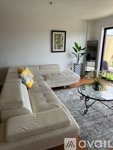 A living room with a white couch and a grey rug.