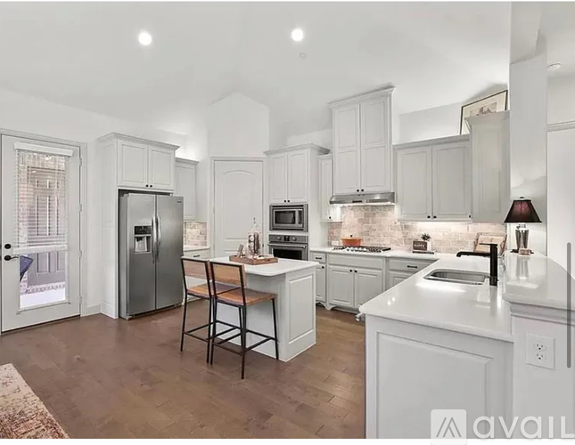 A kitchen with white cabinets and a wooden bar stool.