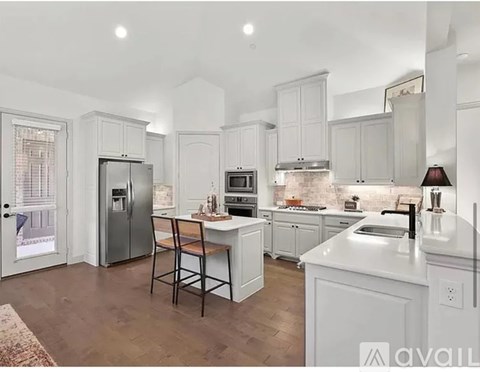 A kitchen with white cabinets and a wooden bar stool.
