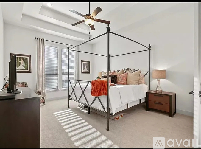 A bedroom with a four poster bed and a ceiling fan.