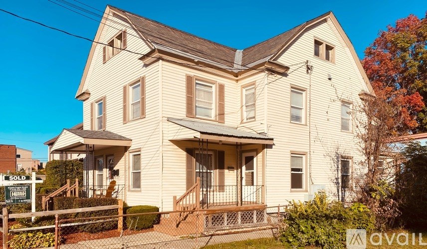 A two-story house with a front porch is for sale.
