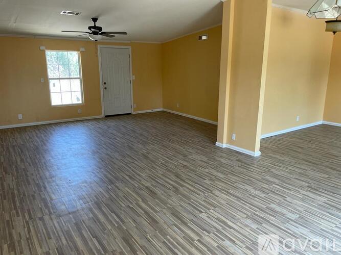 A room with a ceiling fan and wooden flooring.