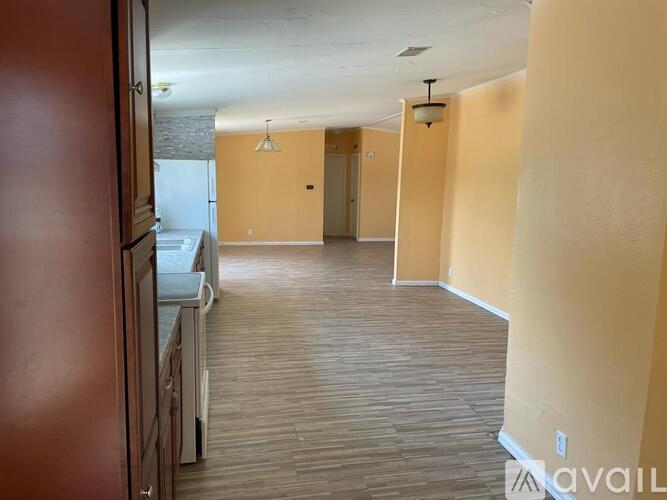 A kitchen area with a refrigerator, cabinets, and a countertop.