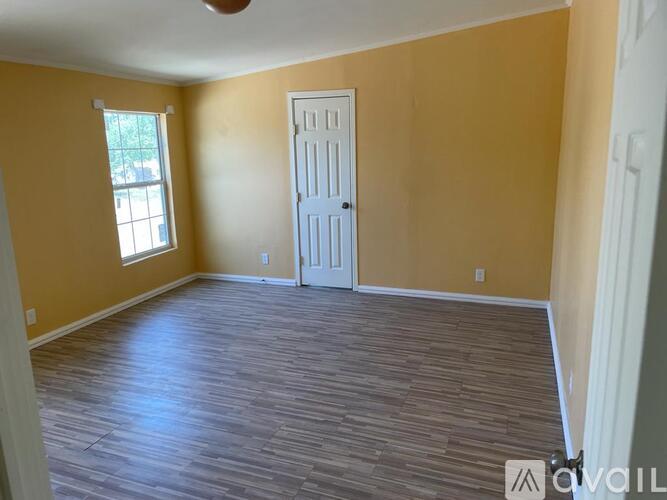 A room with a white door and a window with a view of a tree.