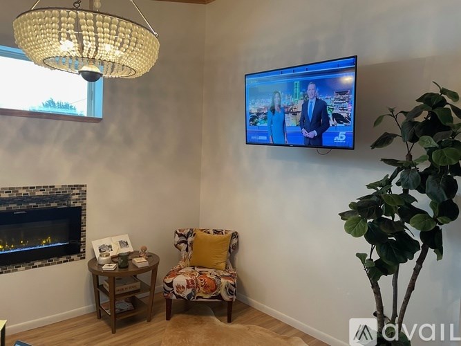 A living room with a television on the wall and a plant to the right.