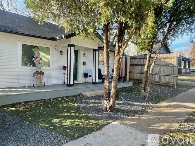 A white house with a green door and a porch with a white railing.