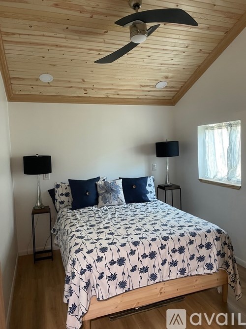 A bedroom with a bed, a ceiling fan, and a window.