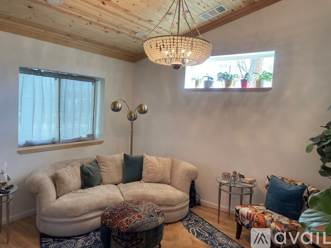 A living room with a beige couch, a small table, and a chandelier.