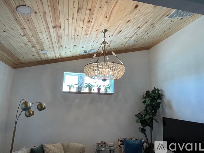 A living room with a wooden ceiling and a hanging light fixture.