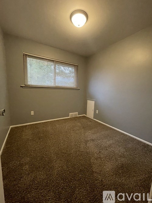 A room with a carpeted floor and a window with blinds.