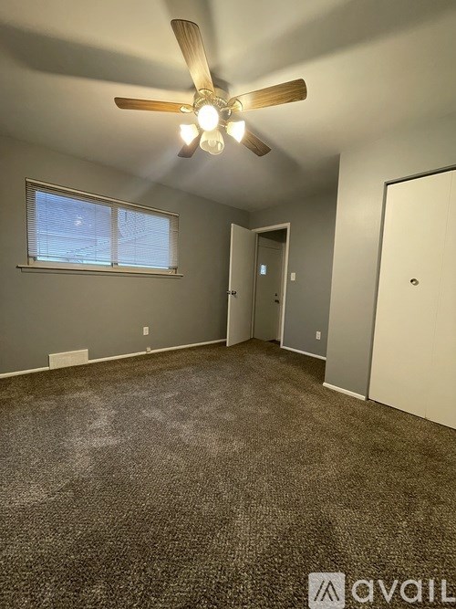 A room with a ceiling fan and carpeted floor.