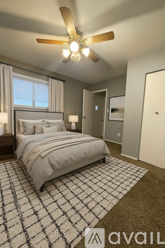 A bedroom with a bed, a ceiling fan, and a rug.