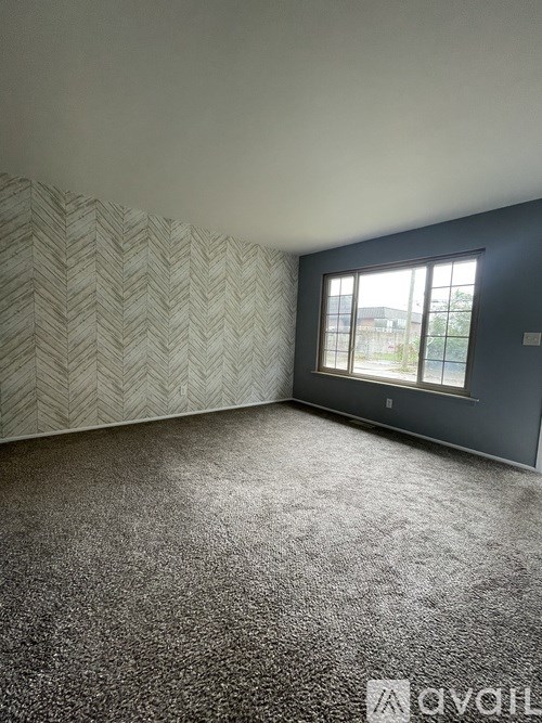 A room with a chevron patterned wallpaper and a carpeted floor.