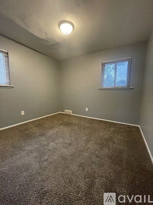 A room with a carpeted floor and a window with blinds.