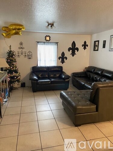 A living room with a Christmas tree and two leather couches.