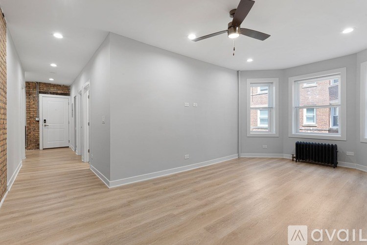 A spacious room with wooden floors and a ceiling fan.