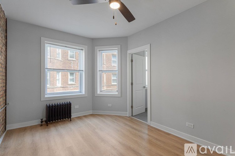 A room with a ceiling fan and two windows.