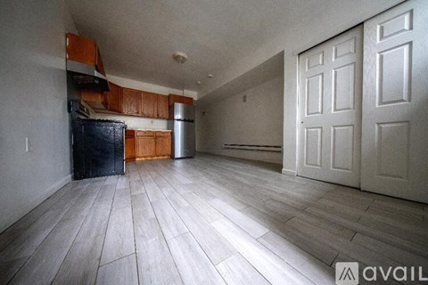A kitchen with wooden cabinets and a black fridge is available for rent.
