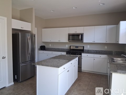 A kitchen with white cabinets and a granite countertop.