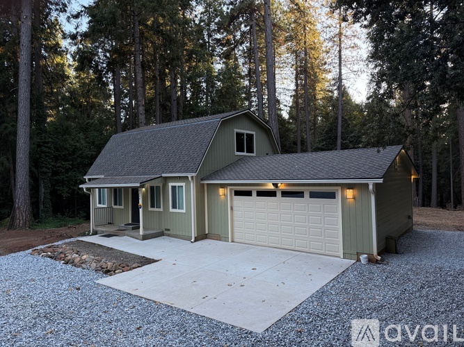 A house with a garage is surrounded by trees.