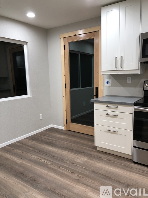 A kitchen with white cabinets and a black fridge.