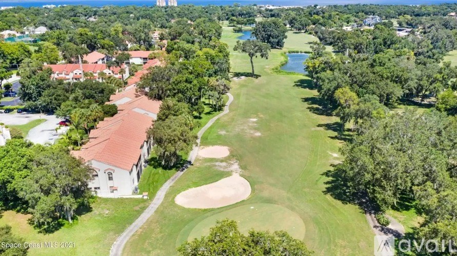 A golf course with a house and a lake in the background.