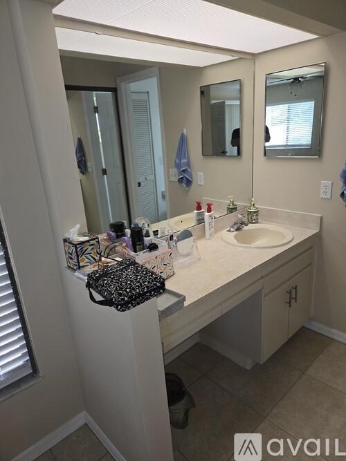 A bathroom with a sink, mirror, and a bag on the counter.