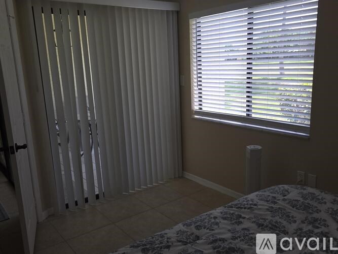 A room with a bed, a window with blinds, and a door with a handle.