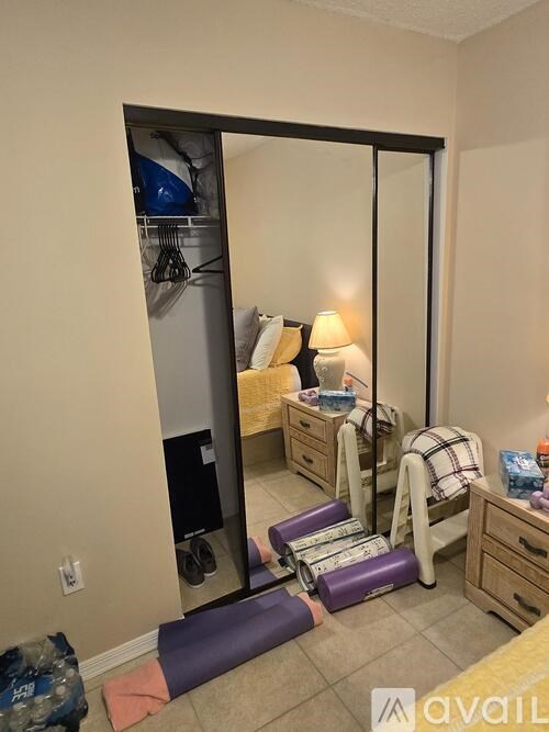 A room with a mirror, a bed, and a chair.
