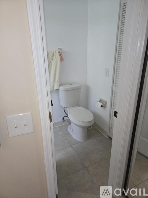 A white toilet in a bathroom with a white wall and a white door.