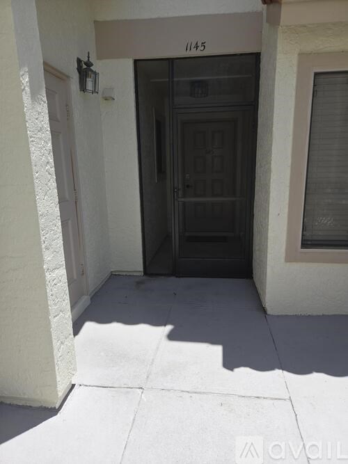 A black door with a glass panel is set in a white wall.