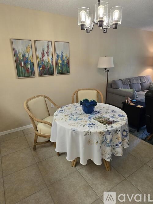 A dining room with a round table covered in a floral tablecloth and two chairs.