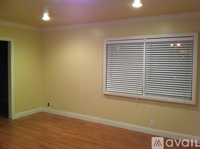 A room with wooden floors and a window with blinds.