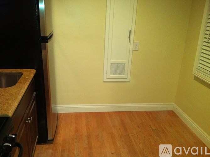 A kitchen with a black fridge and wooden floors.