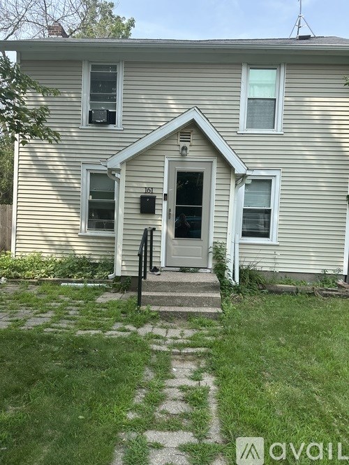 A house with a white door and windows with a small front yard.