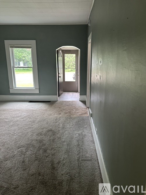 A room with a carpeted floor and a doorway leading to another room.