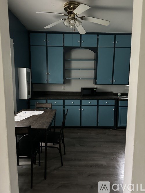 A kitchen with blue cabinets and a ceiling fan.