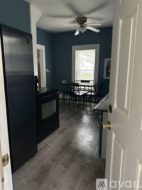 A kitchen with a black refrigerator and a ceiling fan.