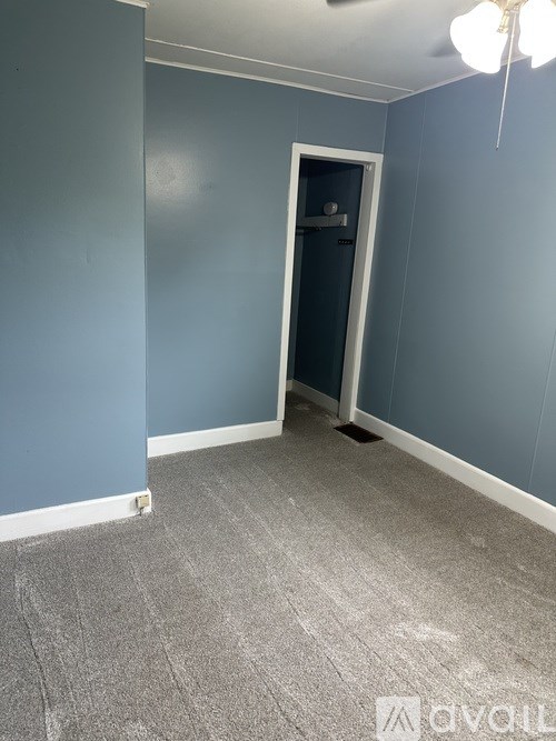 A room with a grey carpet and a door.