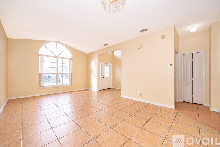 A spacious room with tiled flooring and a chandelier.