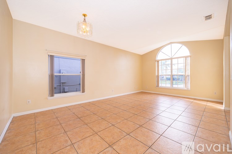 A spacious room with tiled flooring and two windows.