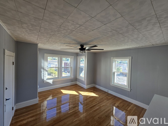 A room with a ceiling fan and two windows.