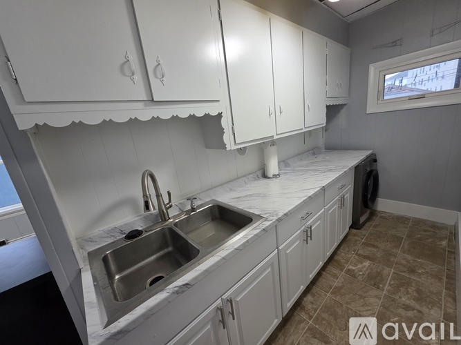 A kitchen with white cabinets and a marble countertop.