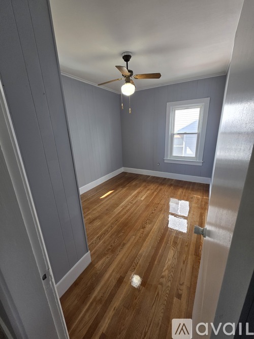 A room with wooden flooring and a ceiling fan.