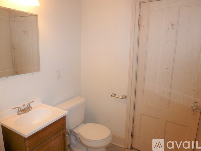 A bathroom with a toilet, sink, and mirror.