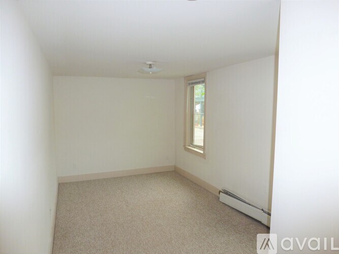 A small, empty room with a carpeted floor and a window.