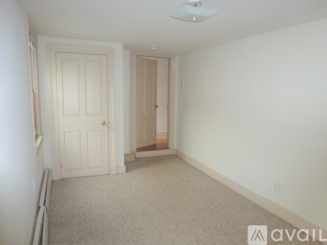 A carpeted room with a door and a small staircase.