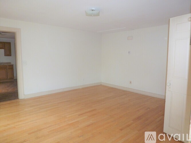 A room with wooden flooring and white walls.