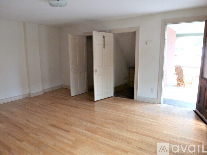 A room with wooden floors and white walls, with a doorway leading to another room.